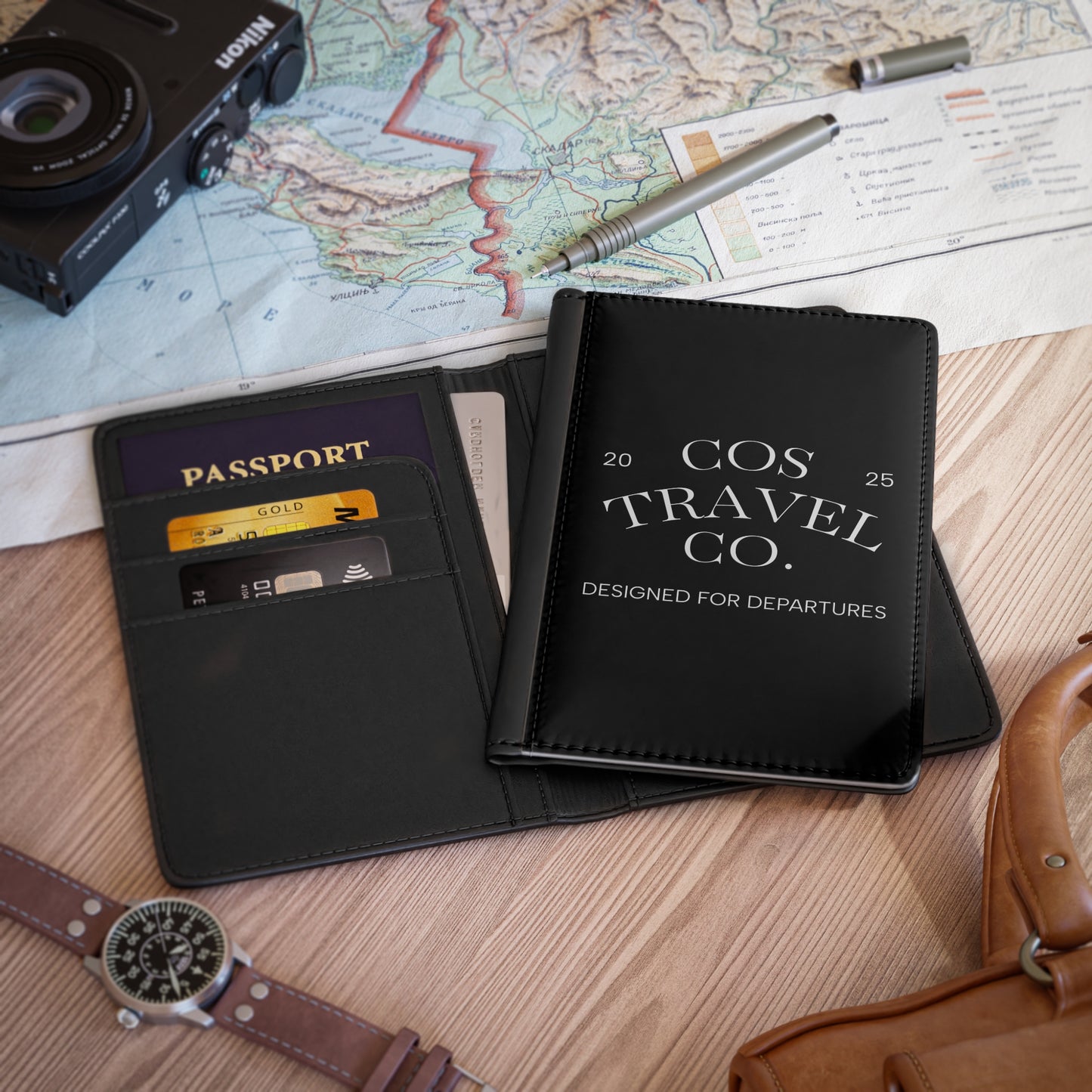 Black travel wallet with 'COS Travel Co.' branding on a map background