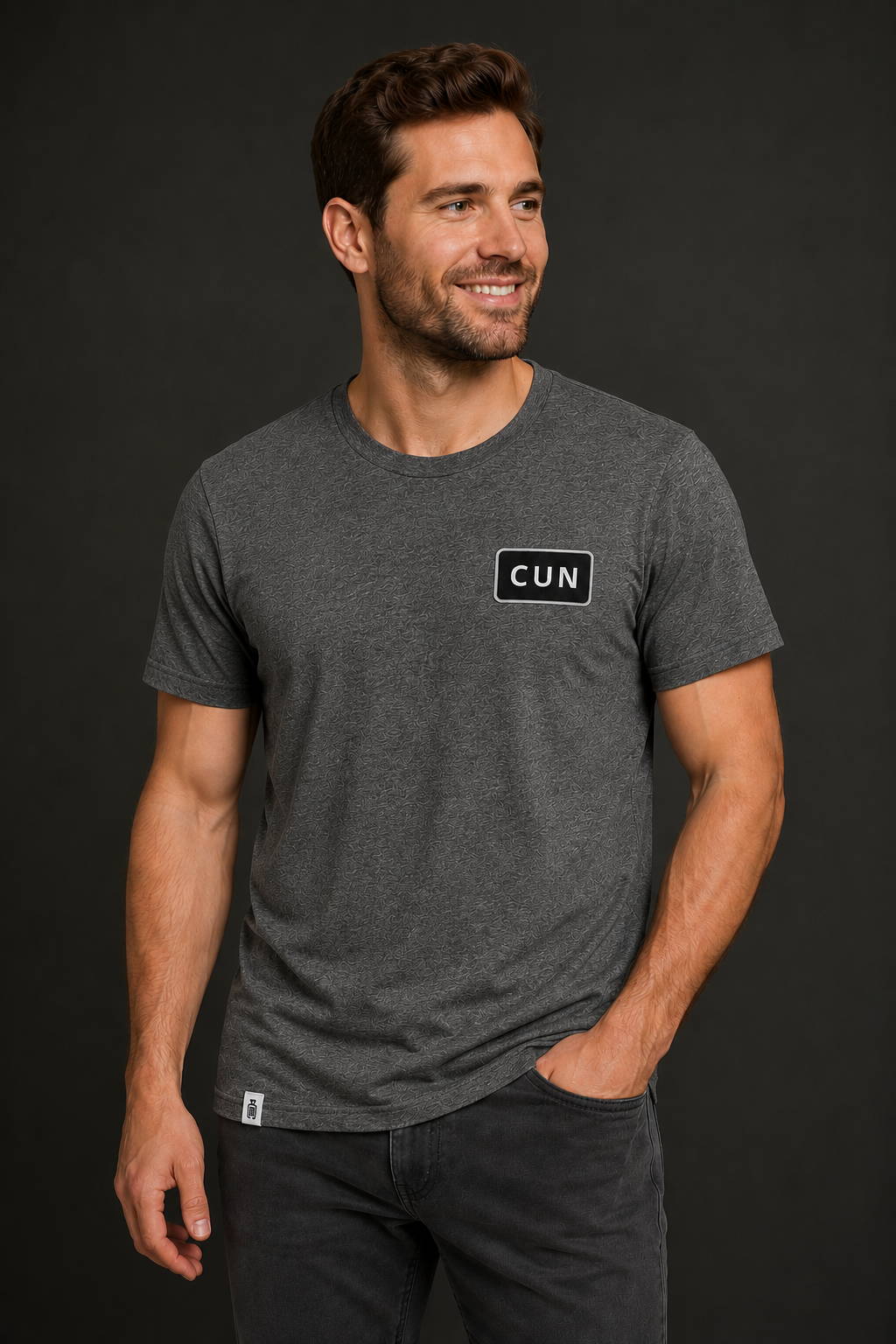 Man wearing a dark gray t-shirt with a CUN on a black background