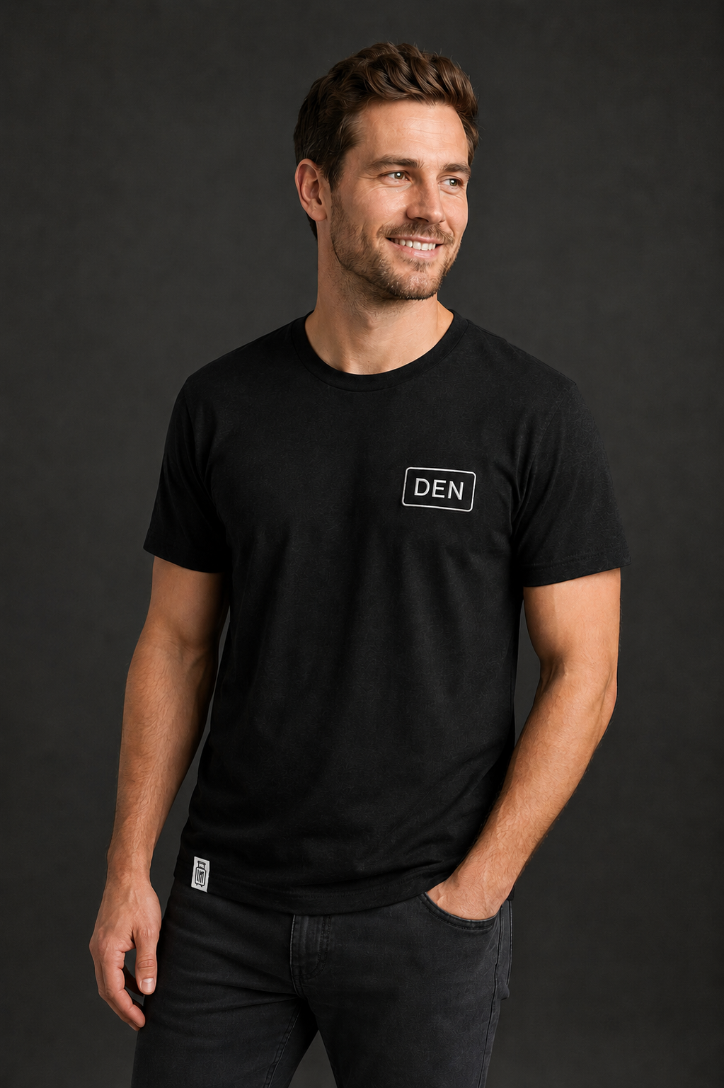 Man wearing a black t-shirt with 'DEN' logo on a dark background