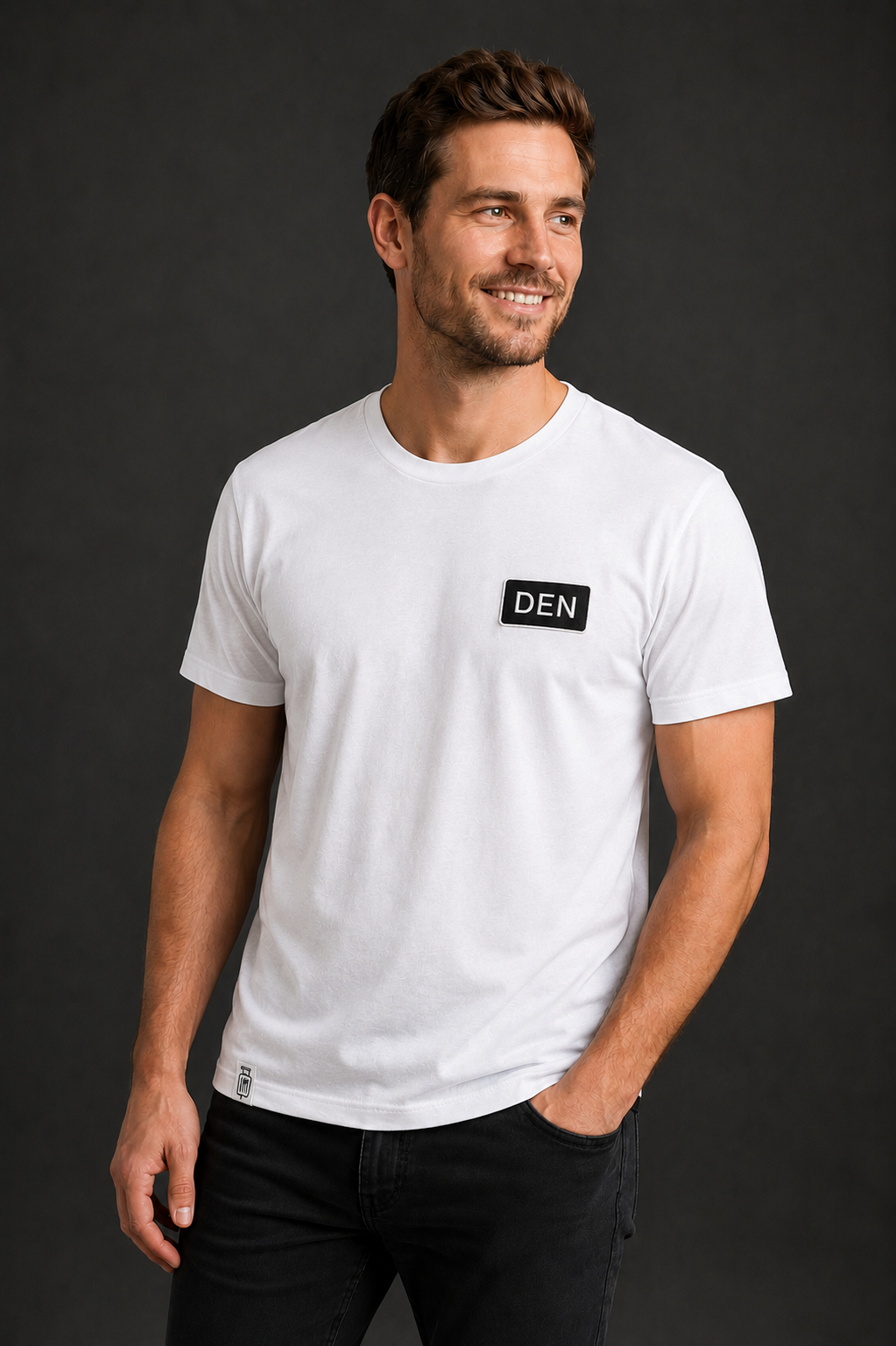 Man wearing a white t-shirt with a DEN patch on a dark background