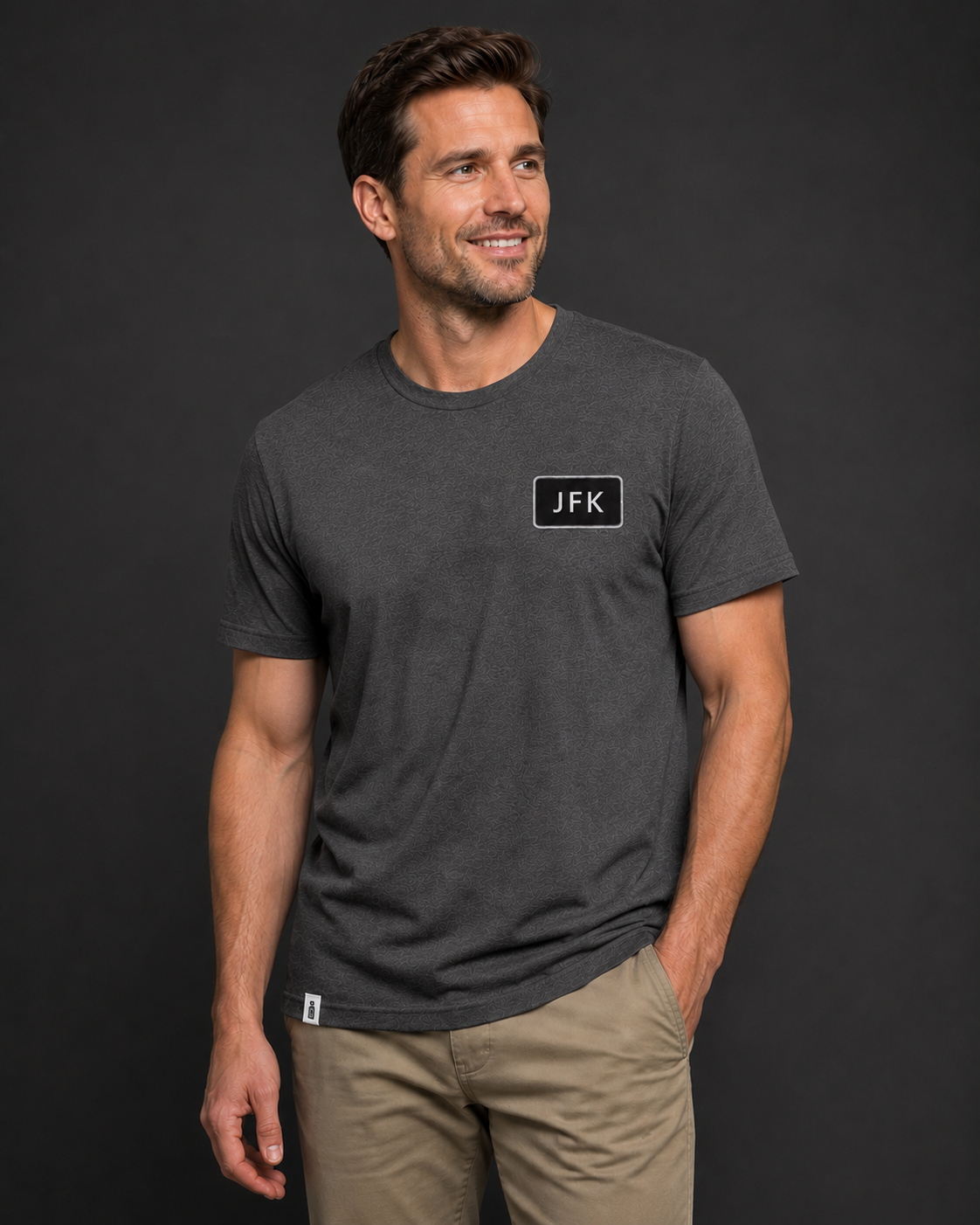 Man wearing a dark gray t-shirt with 'JFK' logo on a black background