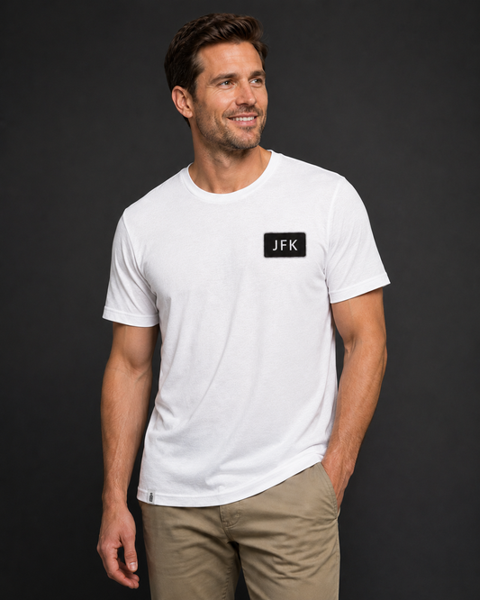 Man wearing a white t-shirt with a logo on a dark background